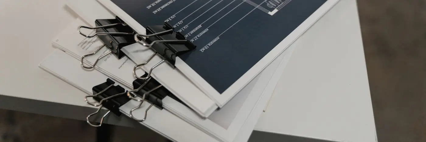 Bound sets of technical drawings clipped together on a desk.