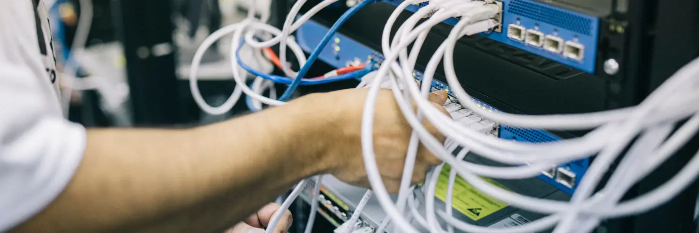 A technician connecting network cables to equipment inside a rack.