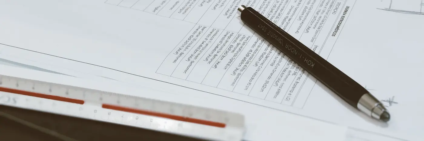 A technical drawing with a specification schedule, a pen and a scale ruler.
